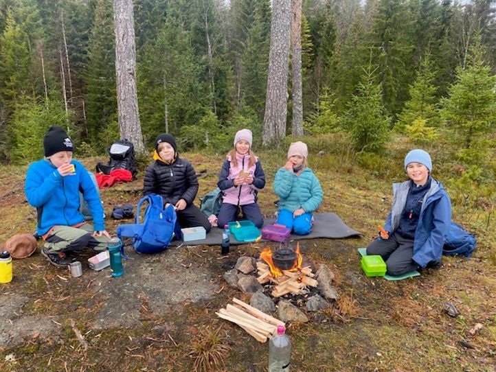 En gruppe mennesker som sitter rundt et bål i skogen
