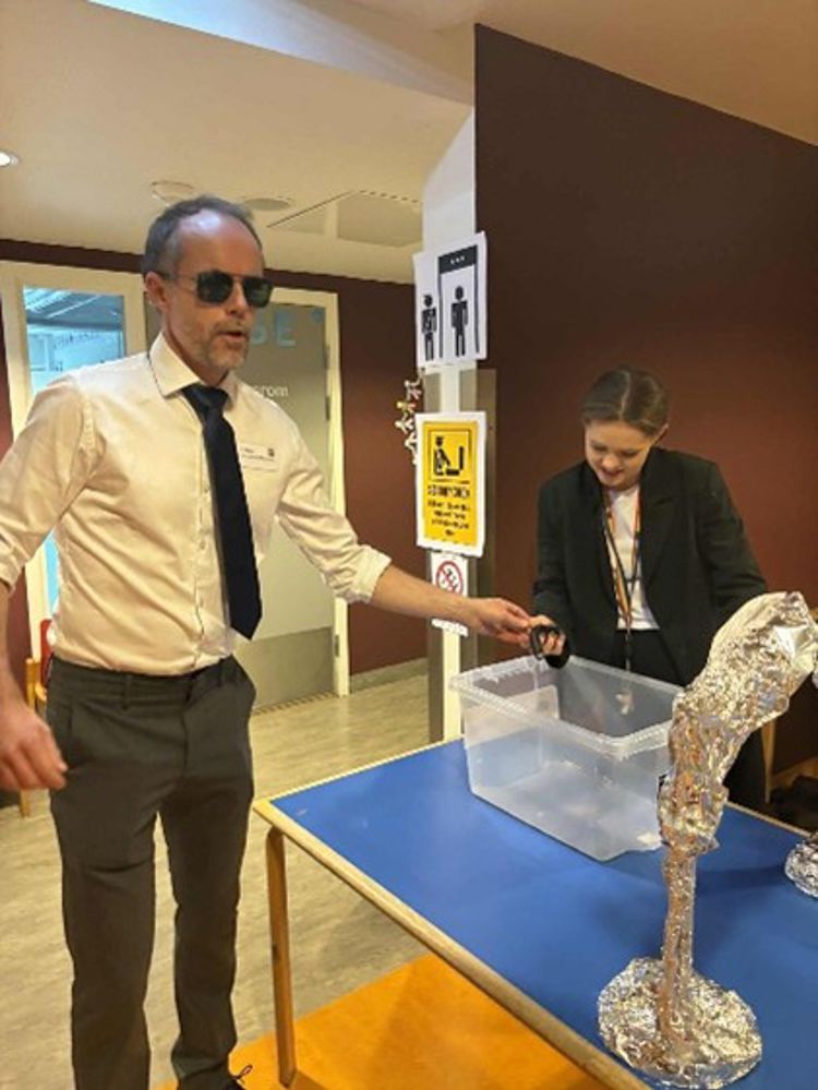 en person i dress og slips som står ved siden av en modell av et skip