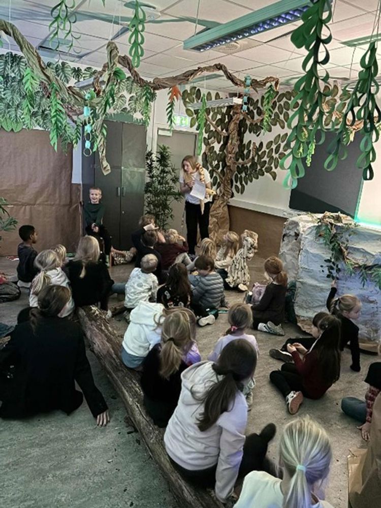 en gruppe mennesker som sitter på gulvet og ser på en person som snakker