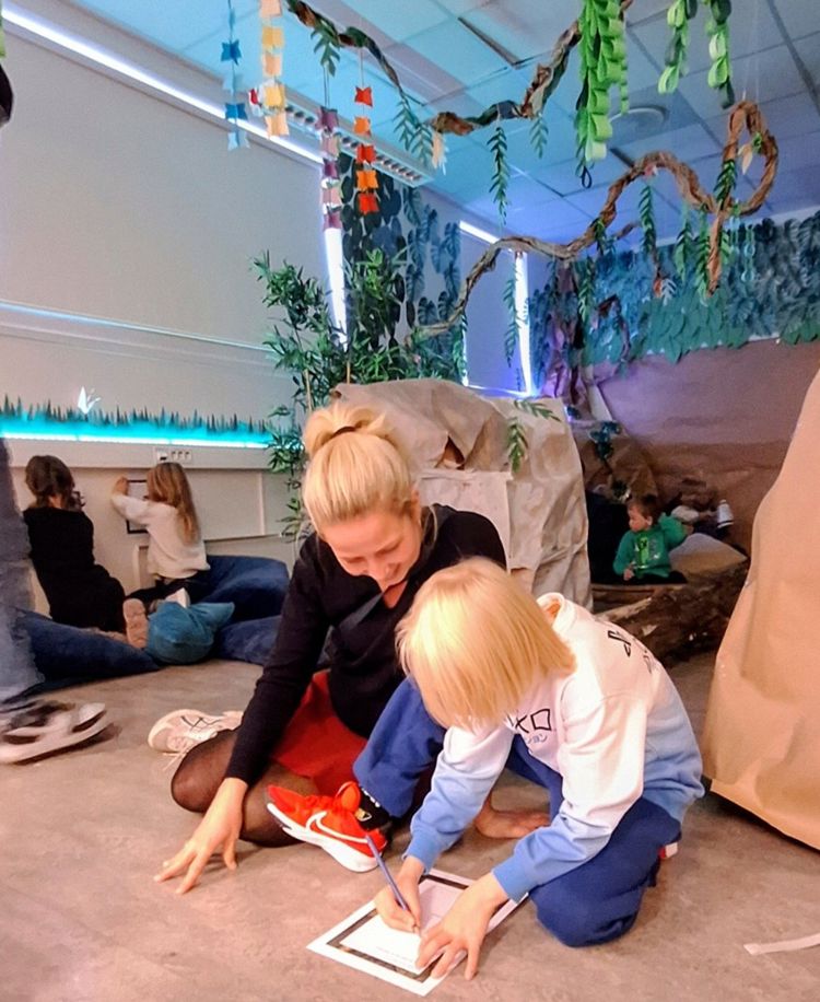 en gruppe barn som sitter på gulvet og skriver på papir en gruppe barn som sitter på gulvet og skriver på papir