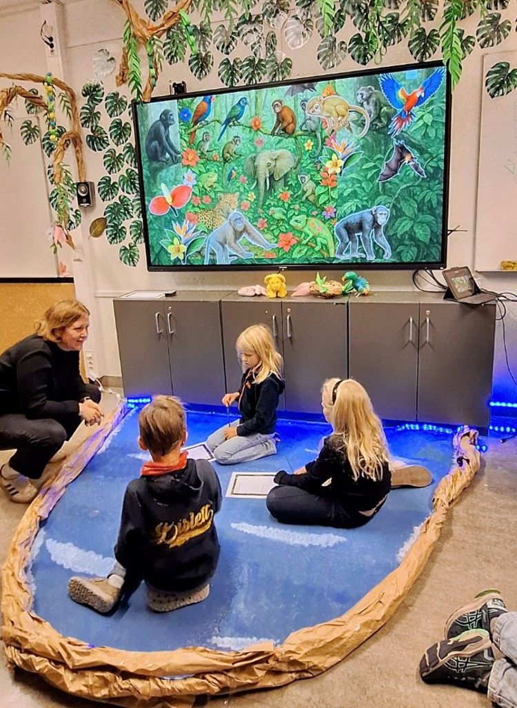 en gruppe mennesker som sitter på gulvet og ser på en skjerm en gruppe mennesker som sitter på gulvet og ser på en skjerm