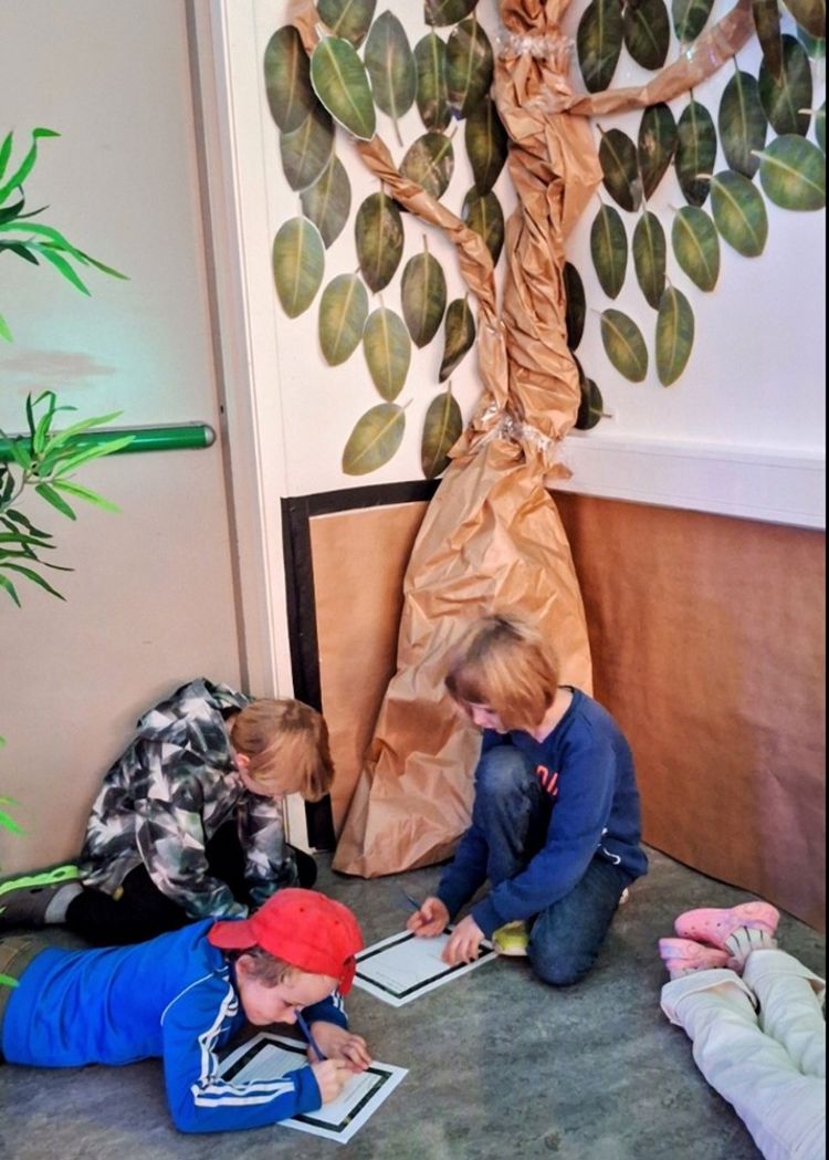 en gruppe barn som sitter på gulvet og ser på en statue en gruppe barn som sitter på gulvet og ser på en statue