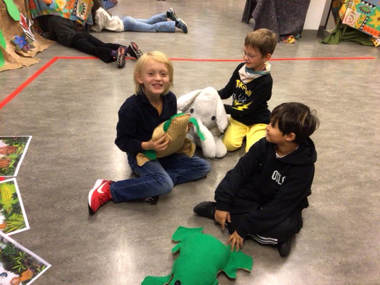 en gruppe barn som sitter på gulvet med et kosedyr