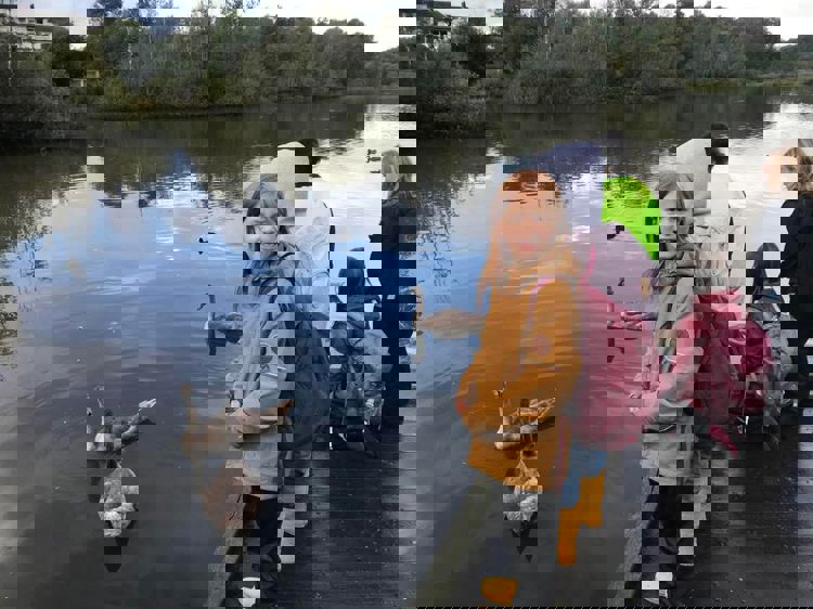 en gruppe mennesker som står ved en vannmasse med ender i