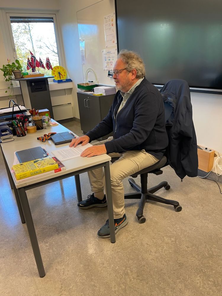 en person som sitter ved et skrivebord en person som sitter ved et skrivebord