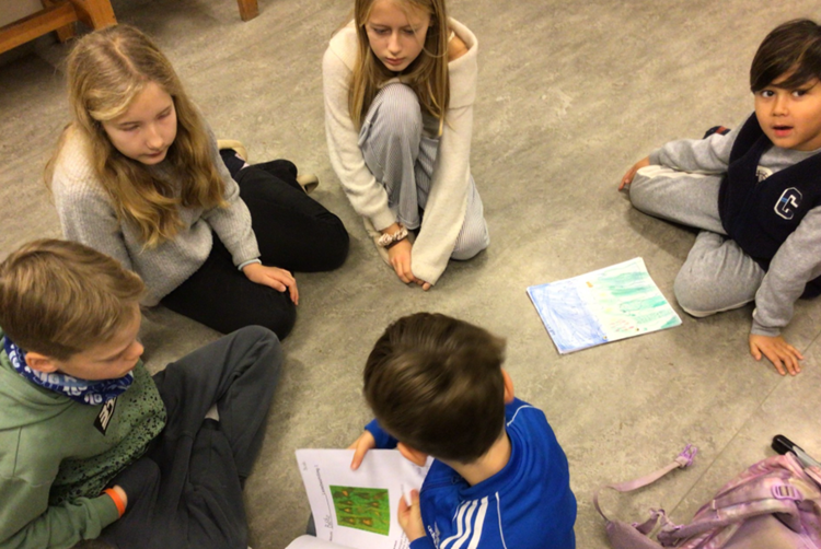 En gruppe mennesker som sitter på gulvet og ser på et papir