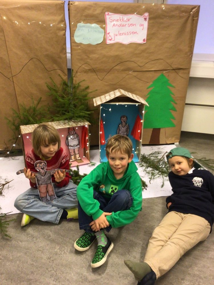 En gruppe barn som sitter på bakken foran en trekonstruksjon