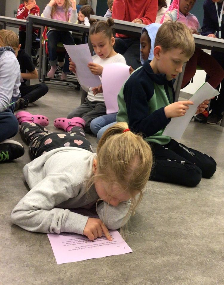 en gruppe barn som sitter på gulvet og leser bøker