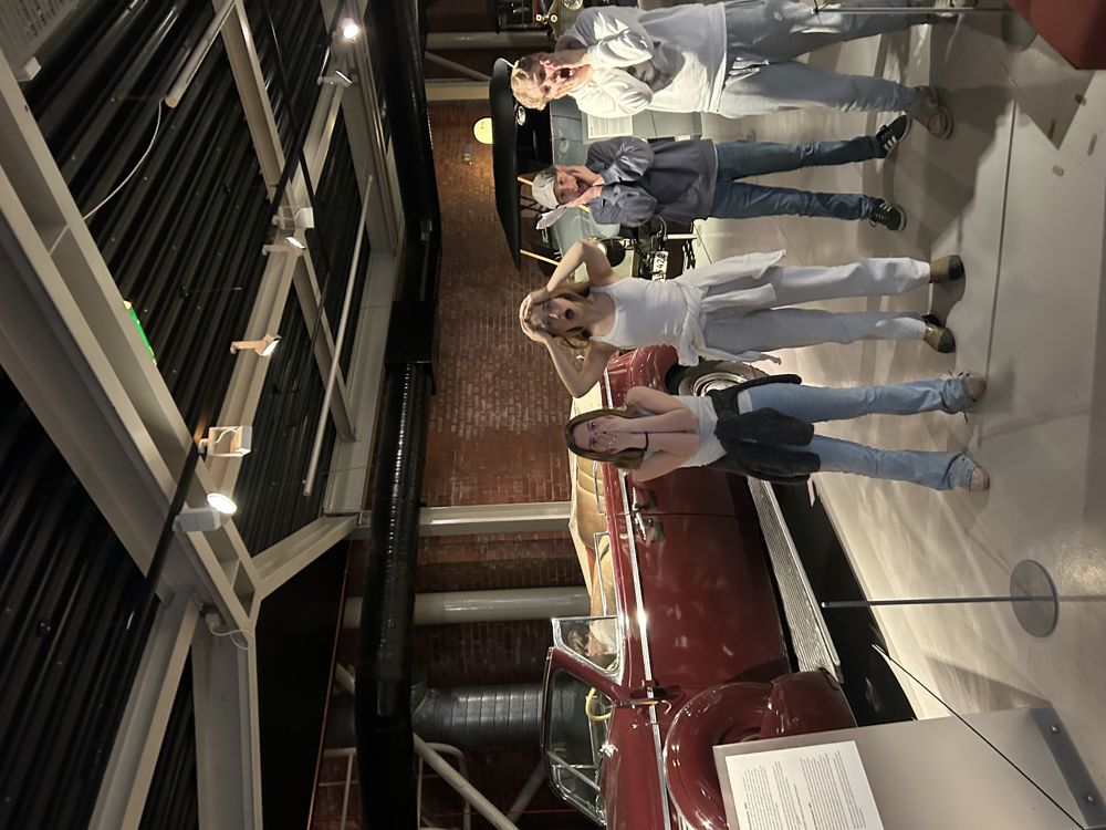 en gruppe mennesker som står foran en bil