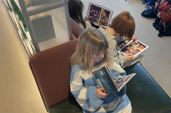 en gruppe barnr som sitter i et rom og leser bøker