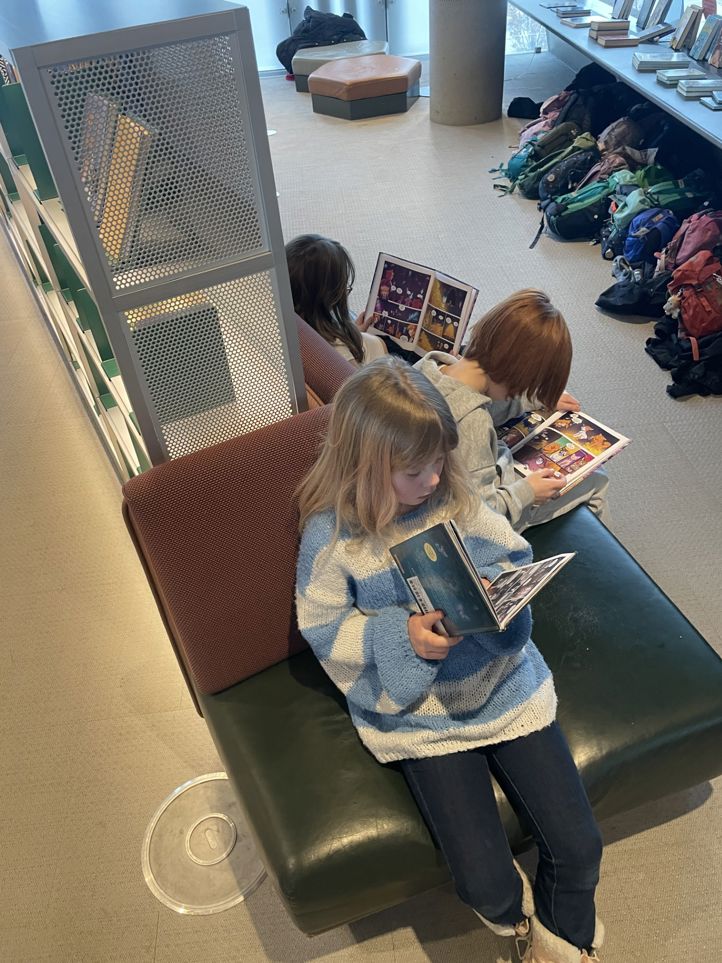 en gruppe barnr som sitter i et rom og leser bøker