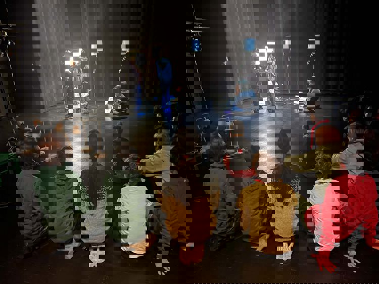 en gruppe mennesker som sitter på gulvet og ser på en person på en scene