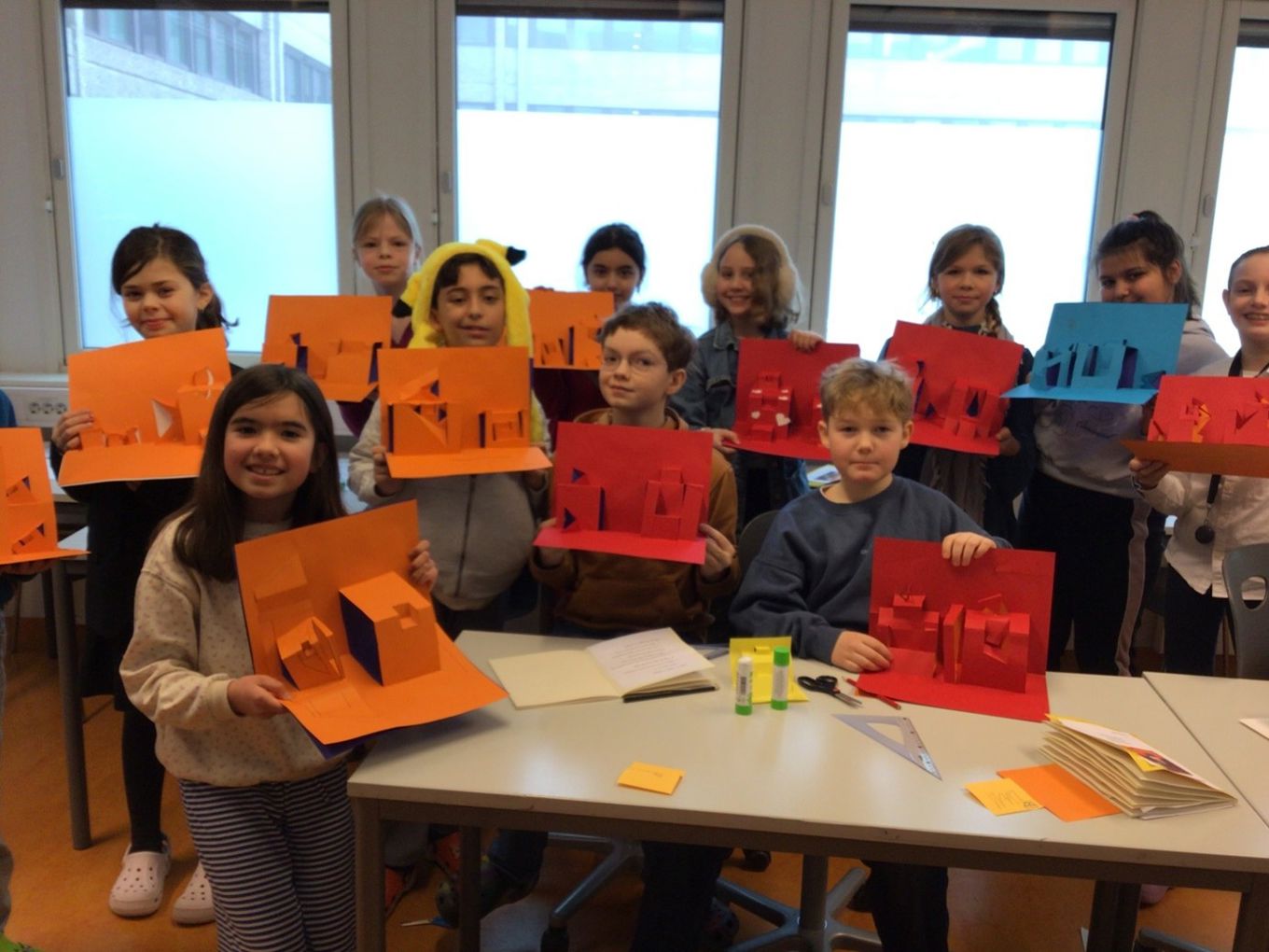 En gruppe barn holder opp oransje og gult papir