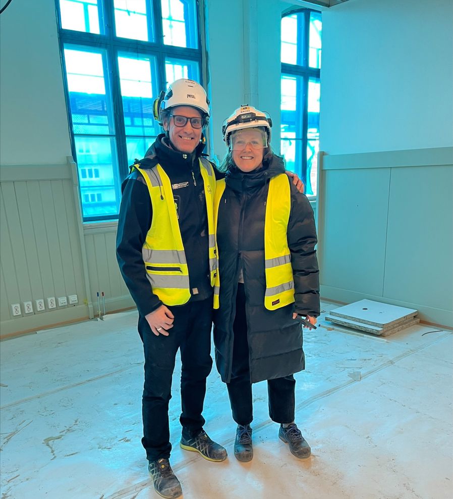 et par menn i sikkerhetsvester som står foran en bygning